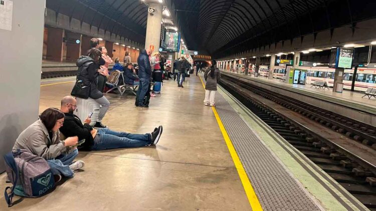 Pasajeros esperando en el andén por retraso de tren de Renfe en una estación ferroviaria en España