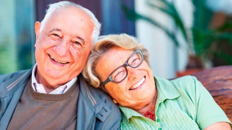 Pareja de jubilados sonrientes tras solicitar online el complemento de brecha de género que eleva su pensión más de 100 € al mes